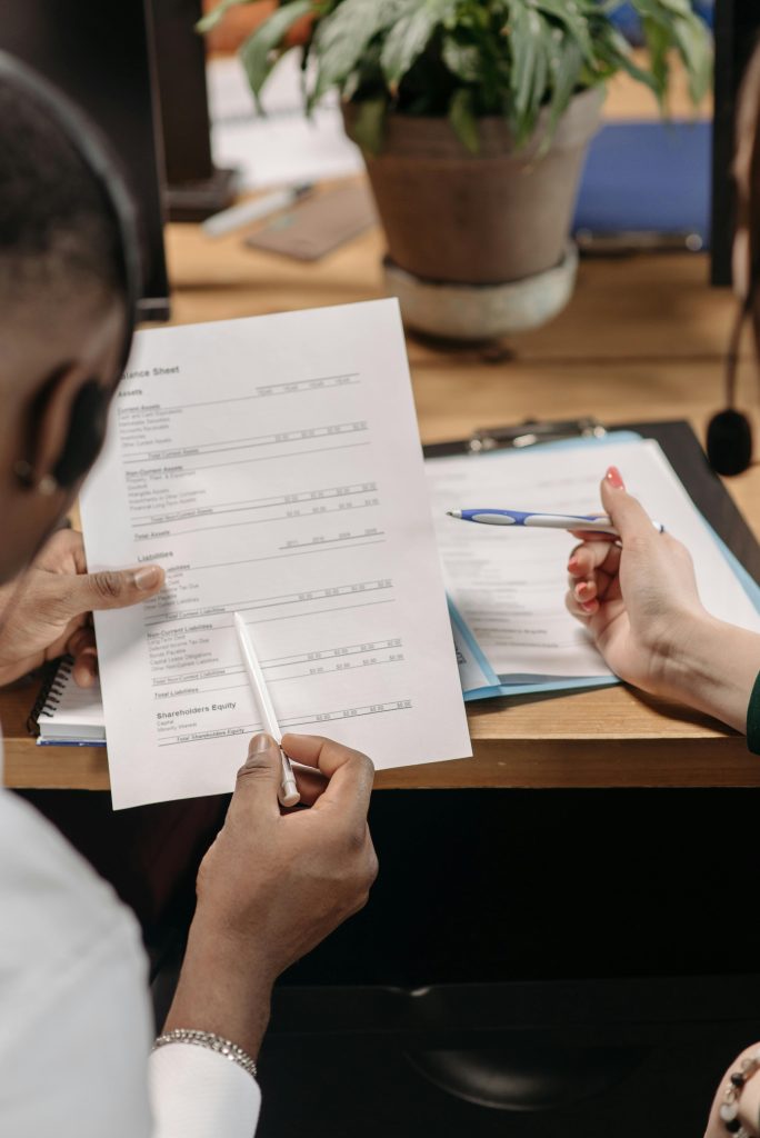 Two professionals reviewing financial documents and discussing strategy in an office environment.